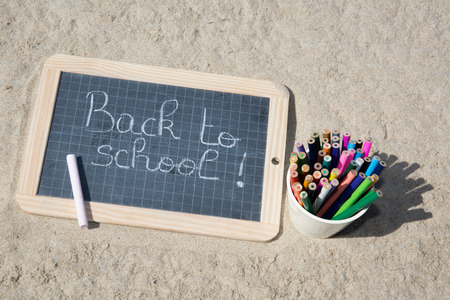 Back to school sign on the beach sand