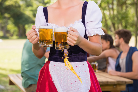 Pretty oktoberfest girl holding beer tankards on a sunny day Stock Photo