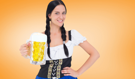 Pretty oktoberfest girl holding beer tankard against orange vignette