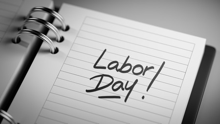 Closeup of a personal agenda setting an important date representing a time schedule the words labor day written on a white notebook to remind you an important appointment