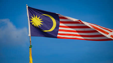 Malaysian flag from left to right with blue sky in the background