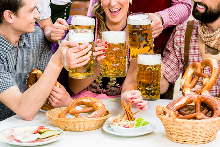 In beer garden friends in tracht dirndl and lederhosen drinking a fresh beer in bavaria munich germany