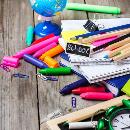 Still life business education concept office and school supplies stationery alarm clock and chalkboard on a rustic wooden table selective focus copy space background Stock Photo