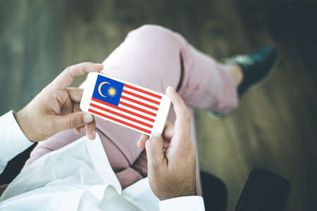 People using smart phone and showing on the screen the flag of malaysia Stock Photo