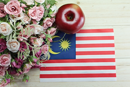 National day malaysia flag apple and flower on wood background