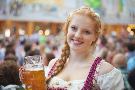 Portrait of cheerful young woman wearing traditional dirndl and holding the 1 liter beer stein at oktoberfest