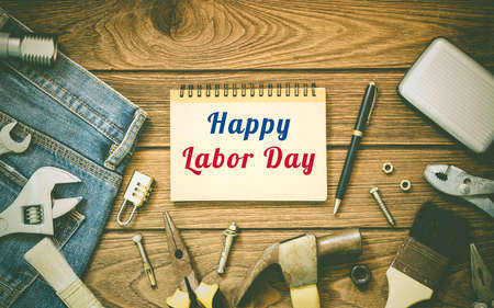 Labor day background concept jeans many handy tools notebook with happy labor day text on wooden background top view