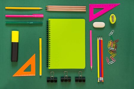 Colorful school supplies green book on green background top view flat lay copy space