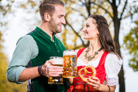 Bavarians in tracht with beer and pretzel in autumn