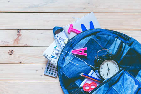 Backpack with school supplies on wooden background