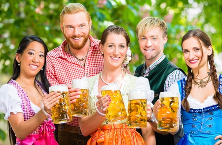 Friends two men three women standing in beer garden with beer glasses