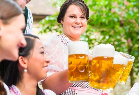 Waitress in beer garden serving drinks to three women and man Stock Photo